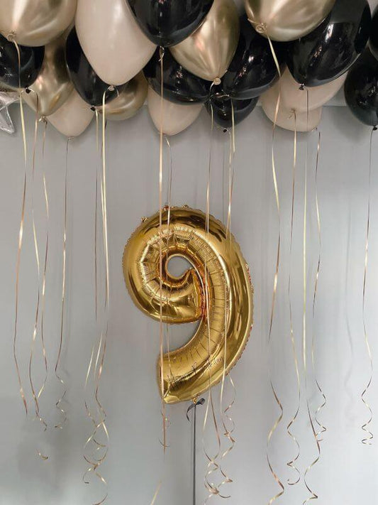 Gold spiral balloon with black, white, and gold balloons on a gray background