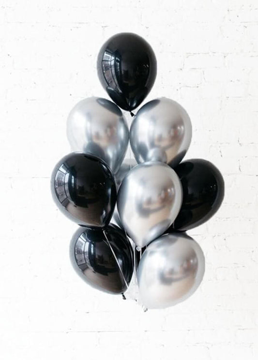 Group of black and silver balloons against a white brick wall background